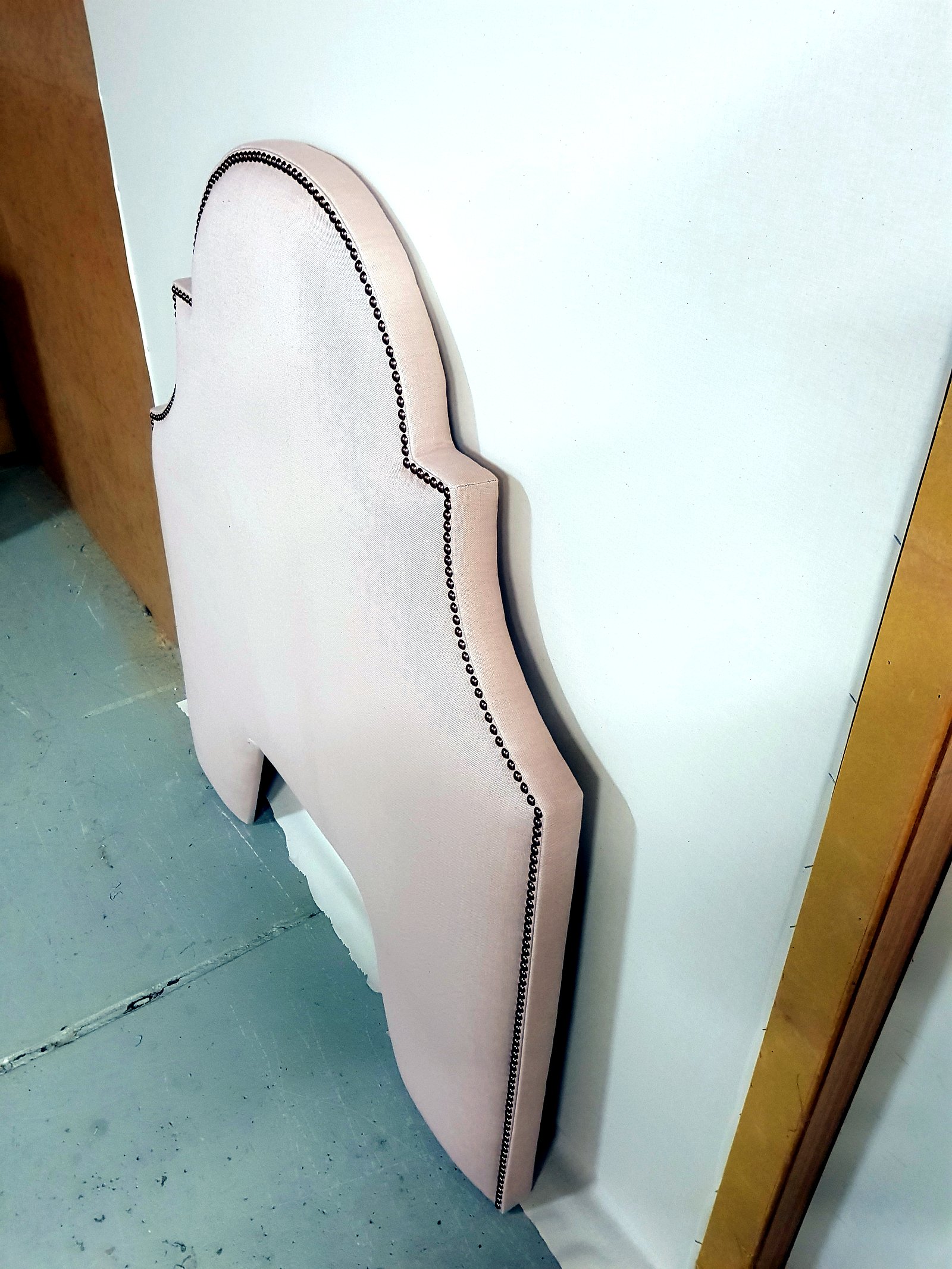 Custom pink linen bed head with brass studwork
