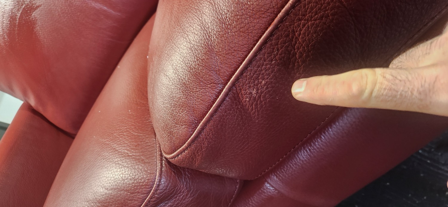 Close-up of the leather being touched up where the dog had scratched the red Natuzzi lounge