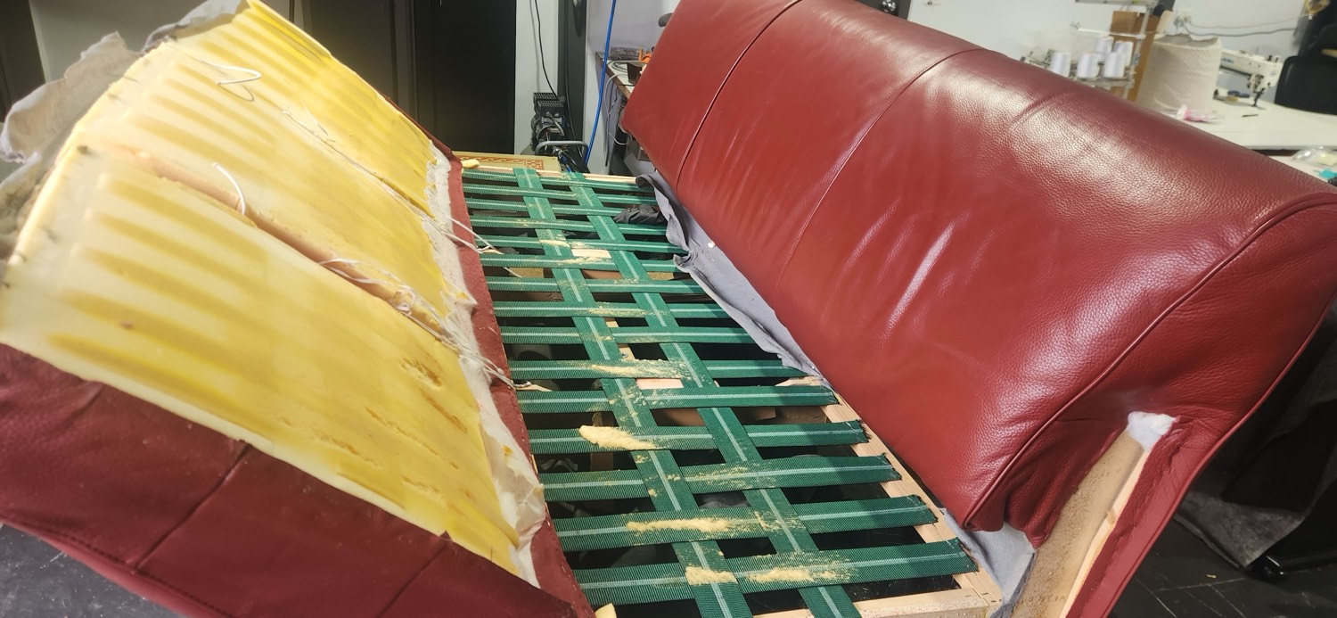 Rewebbing the seat base and stripping out the collapsed old foam on a red leather Natuzzi lounge in our Melbourne workshop