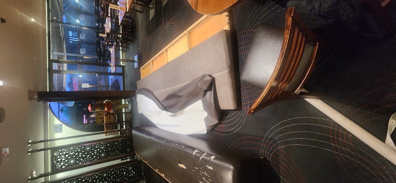 Stripping the worn banquette seat on site at the Veneto Club, plywood base exposed and new cover being fitted